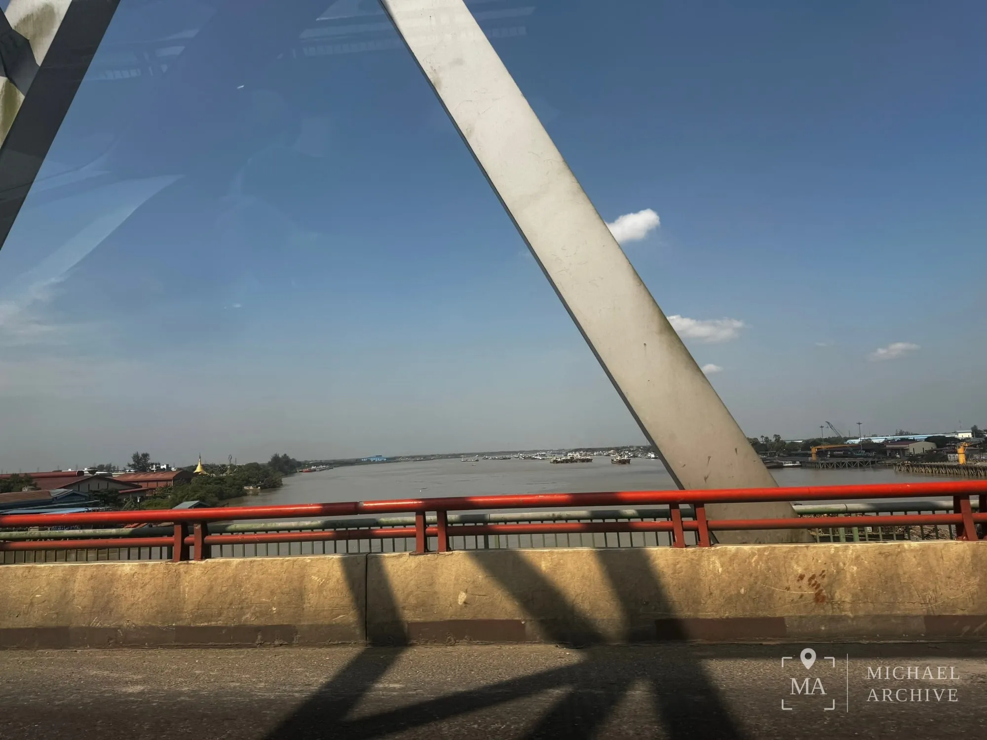 다리 위에서 본 넓은 강. 붉은 난간 너머로 물과 건너편 시설이 보인다.