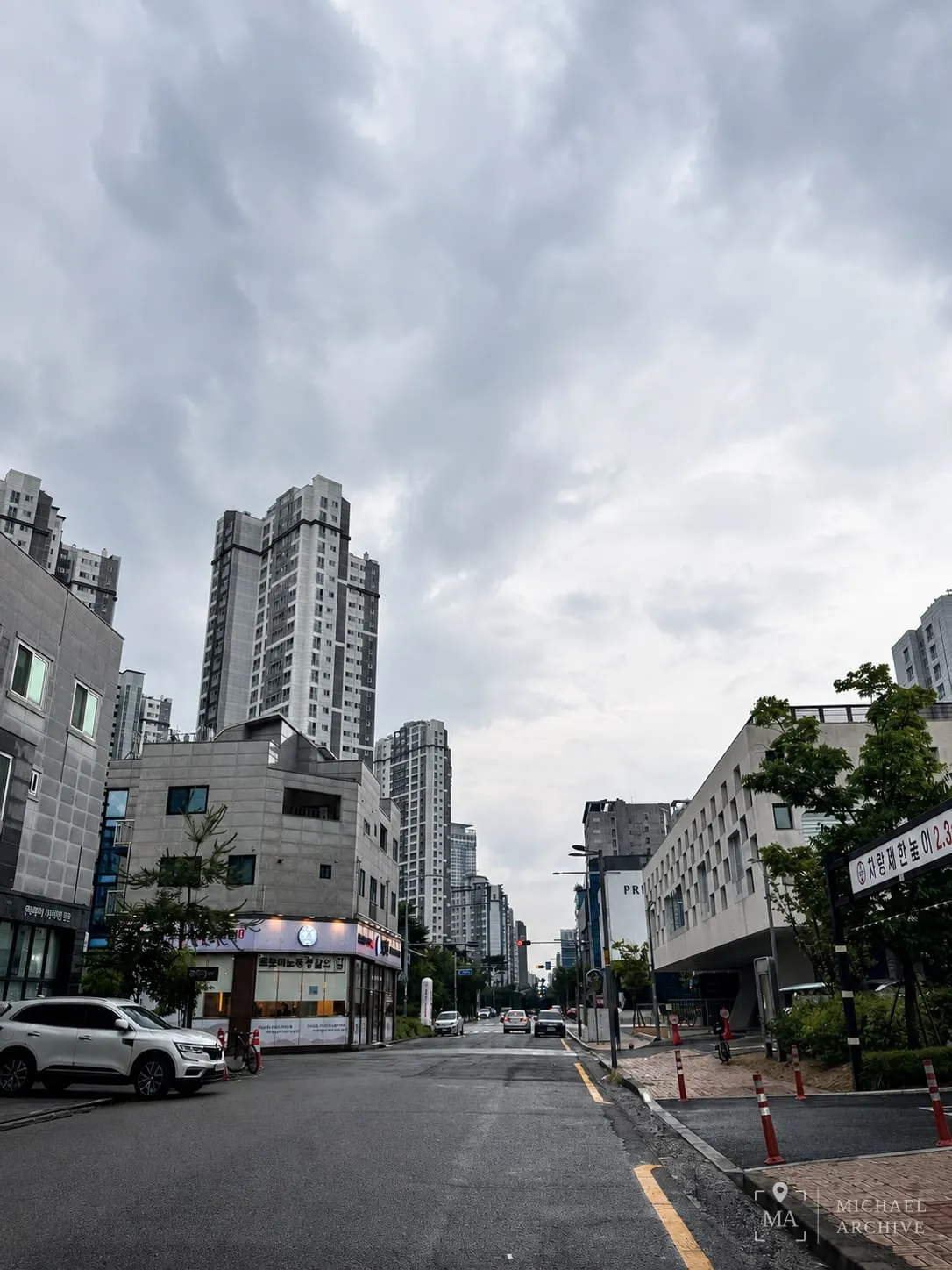 흐린 하늘 아래 청라국제도시의 거리. 젖은 도로와 고층 아파트