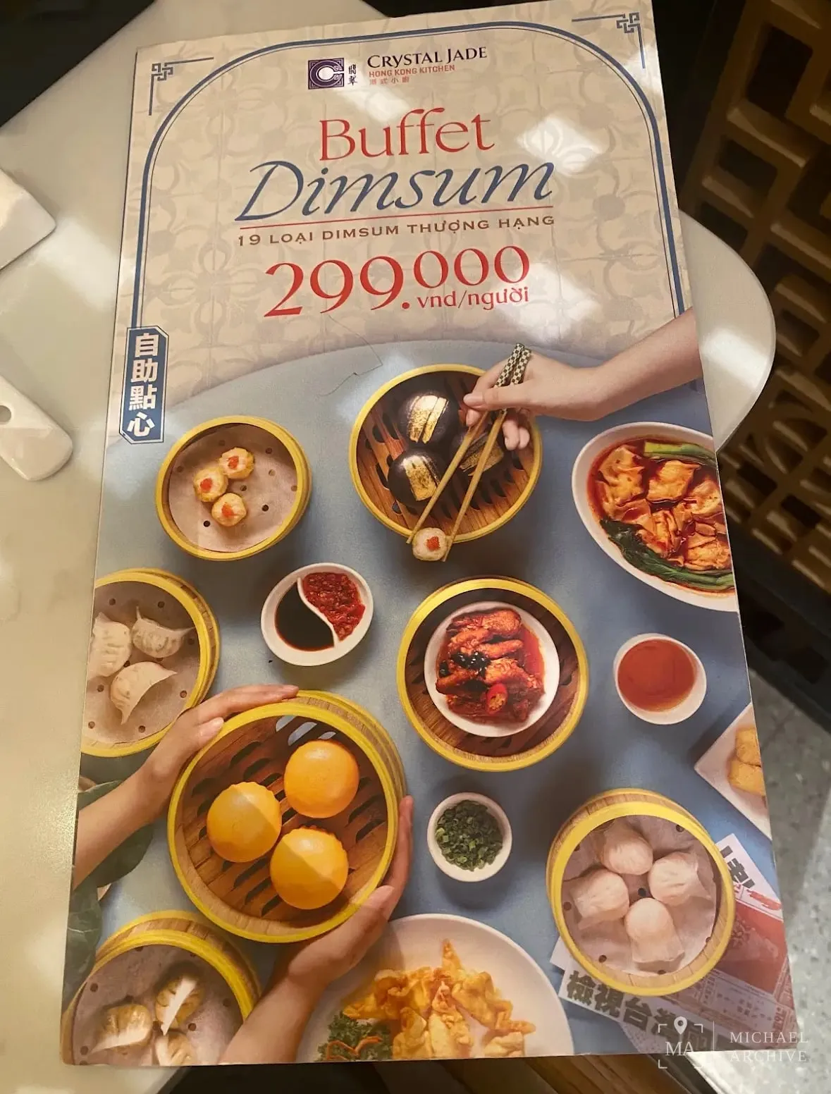테이블 위 크리스탈 제이드 딤섬 뷔페 안내물 — 「Buffet Dimsum · 19 loại dimsum thượng hạng · 299.000 vnd/người」