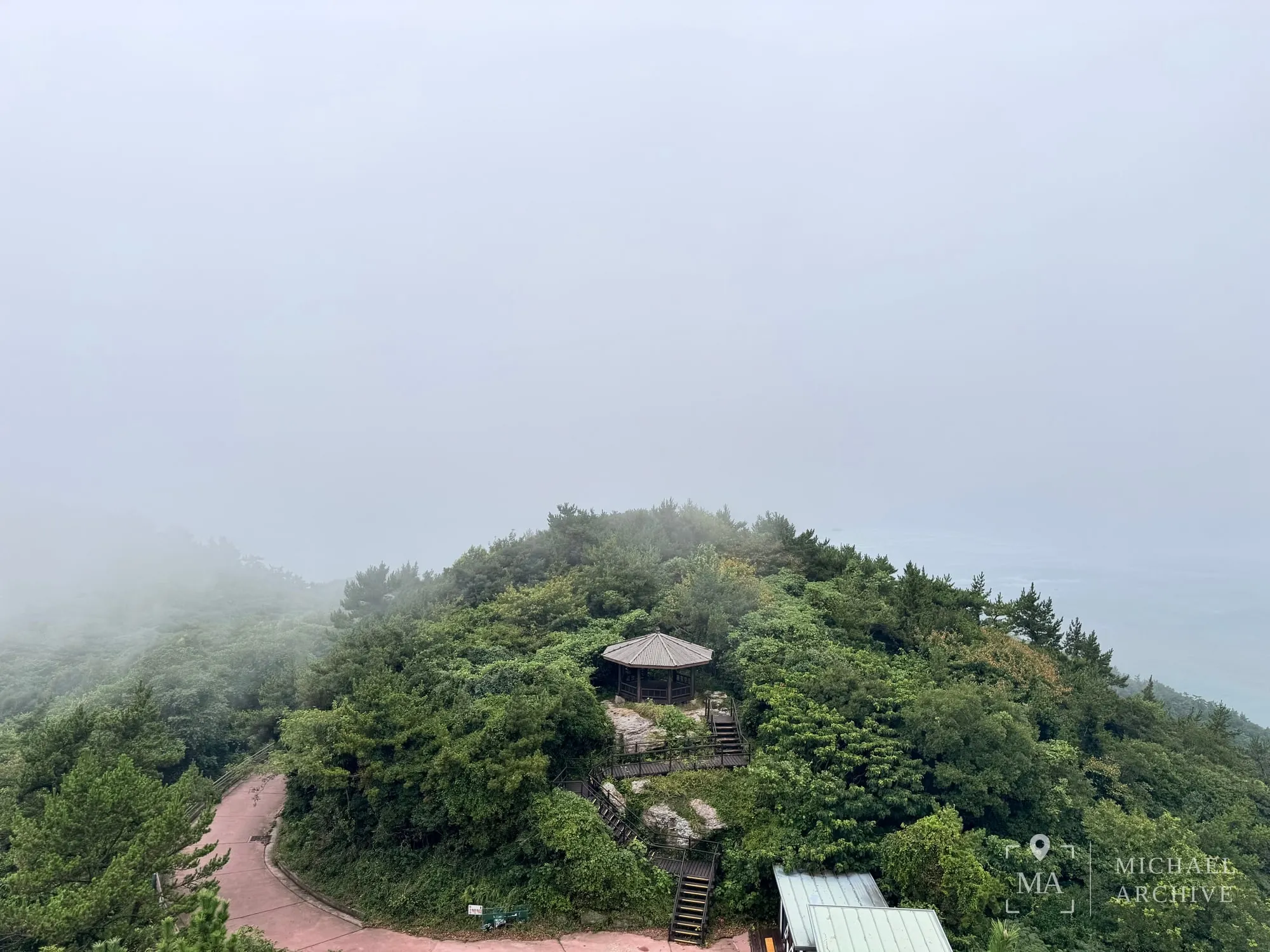 해무에 잠긴 정상의 정자와 산책로