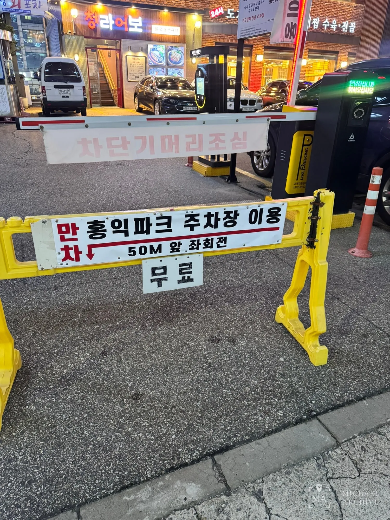 「만차 ↓ 홍익파크 주차장 이용 / 50M 앞 좌회전 / 무료」라고 적힌 안내판