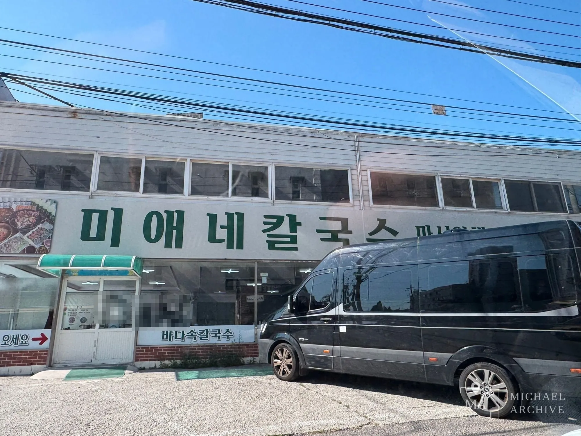 흰 2층 건물 정면에 초록 글씨로 「미애네칼국수」 간판이 크게 걸려 있고, 1층 유리창 아래에 「바다속칼국수」 띠 간판이 붙어 있다