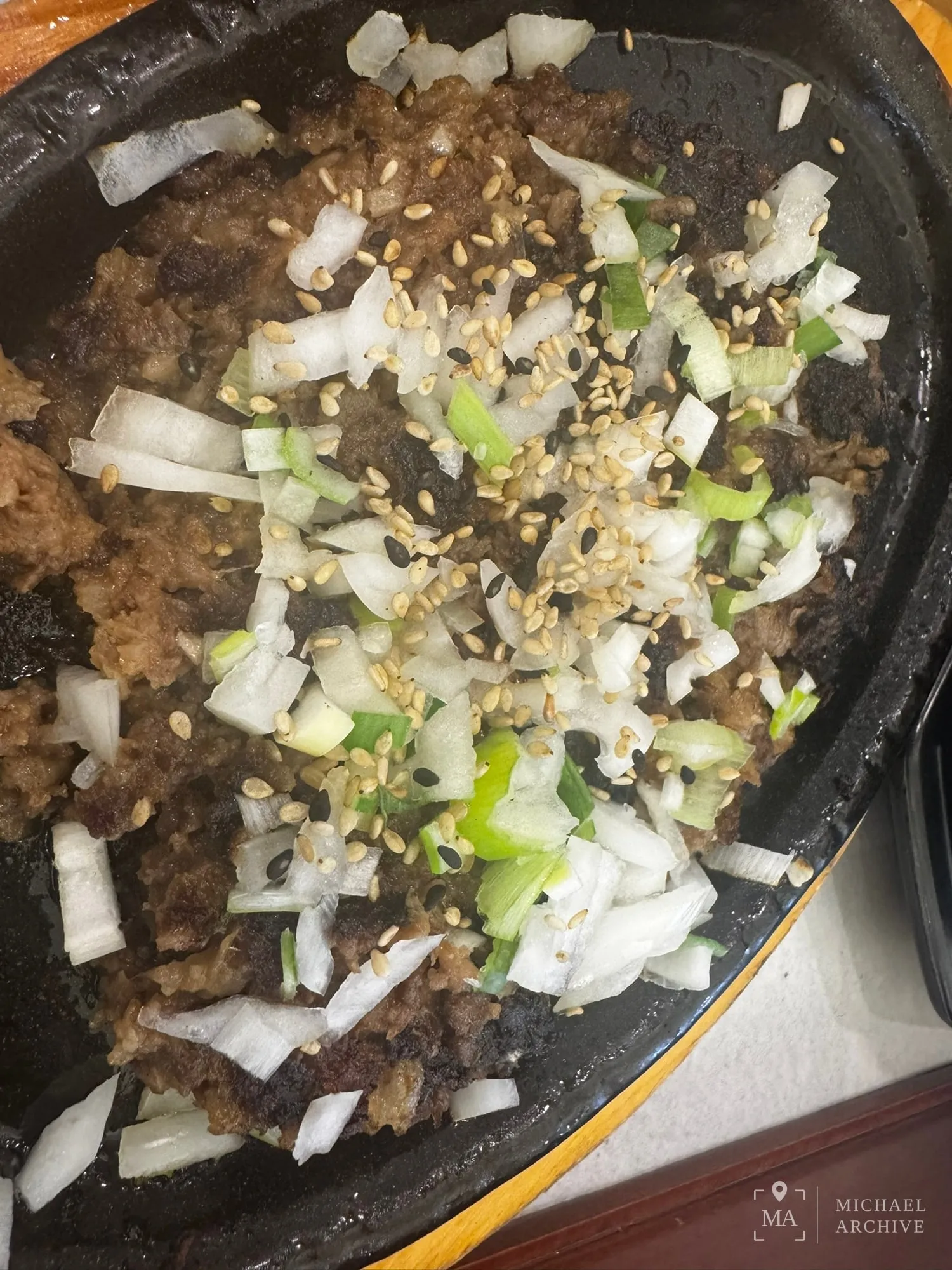 떡갈비 클로즈업 — 다진 고기 위에 양파와 대파, 통깨